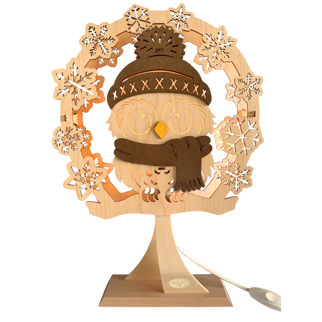 Dekolicht mit Eulenmotiv. Die Eule trägt eine Mütze und Schal in Braun gehalten. Der Rest ist Naturholz. Sie steht auf einen Ständer. Beidseitiges Motiv. Hergestellt im Erzgebirge